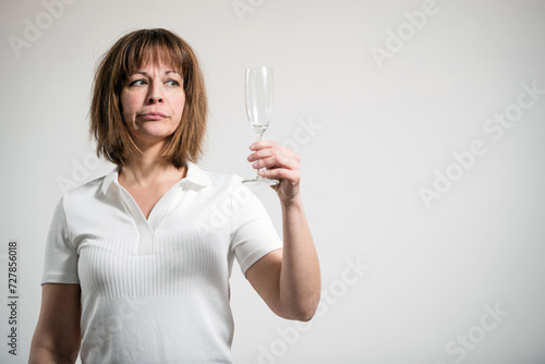 Caucasian woman holding empty champagne glass, white background. Conceptual image of The Dry Challenge.