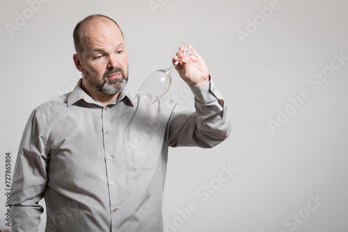 Caucasian man staring at empty wine glass, white background. Conceptual image of The Dry Challenge