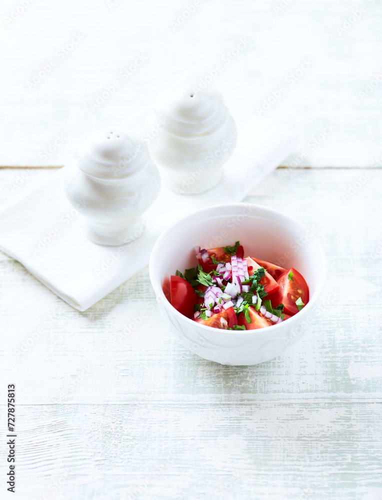 Simple salad with cherry tomatoes, red onion and fresh herbs. Bright wooden background. Close up. Simple salad with cherry tomatoes, red onion and fresh herbs. Bright wooden background. Close up.