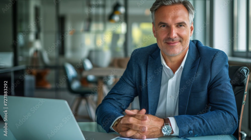 professional middle-aged man sitting at a desk with a laptop professional middle-aged man sitting at a desk with a laptop