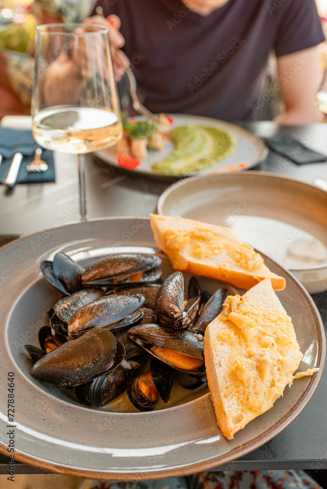 mussels on a plate with slices of bread, served in a restaurant or cafe.