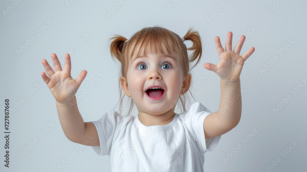 joyful toddler with pigtails is raising her hands in excitement and looking up, set against a plain light background joyful toddler with pigtails is raising her hands in excitement and looking up, set against a plain light background