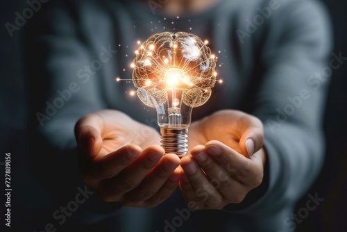 A close-up of a person s hands holding a glowing brain shaped light bulb, representing innovative ideas