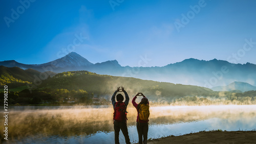 Asian woman and Asian man which backpacking standing near the lake  she was smiling  happy and enjoying the natural beauty of the mist.