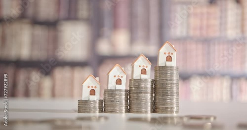 Mortgage loan or home equity loan, financial concept : Tiny model residential house perched atop coin stacks, depicting home loan or borrowing money to purchase a new home for first time homebuyer.	 photo