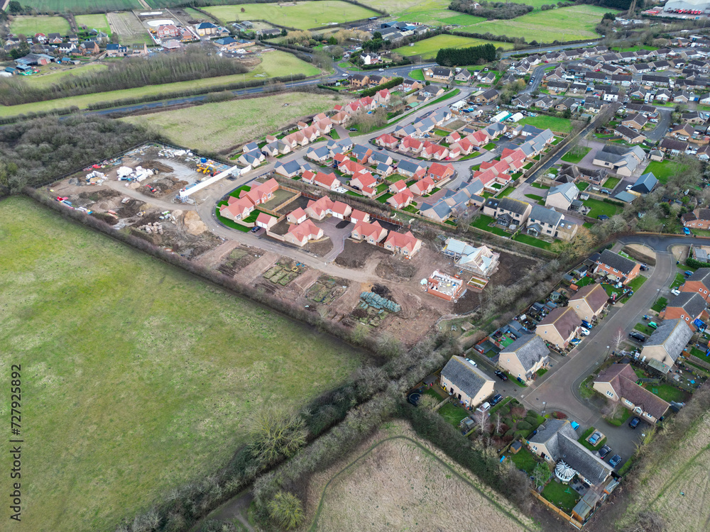 Drone view of a large housing development of detached bungalows in the East of England. Seen near a busy road bypass.