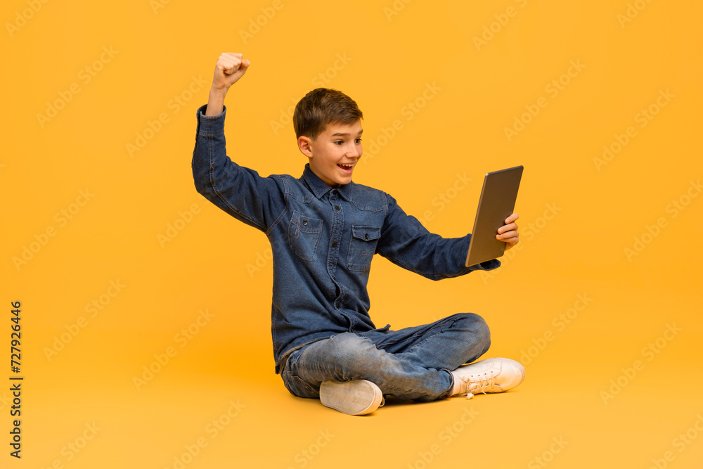 Joyful teen boy celebrating success with digital tablet Joyful teen boy celebrating success with digital tablet