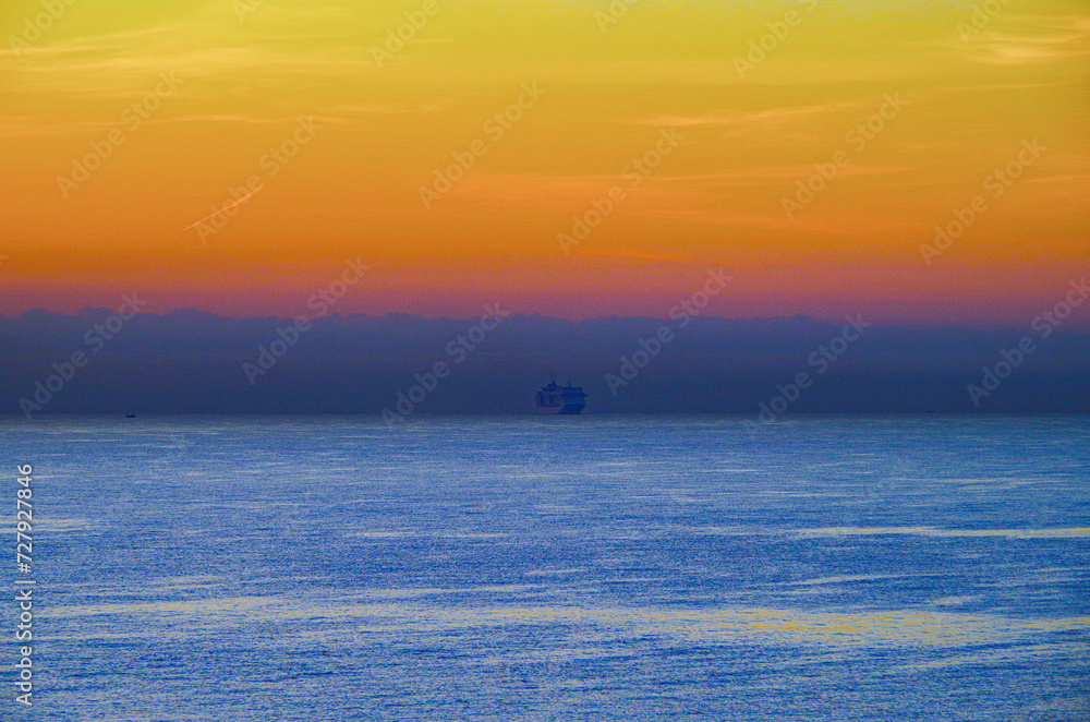 Large modern cruiseship cruise ship liner at the horizon during sunrise sunset blue hour twilight dusk dawn at sea ocean view Large modern cruiseship cruise ship liner at the horizon during sunrise sunset blue hour twilight dusk dawn at sea ocean view