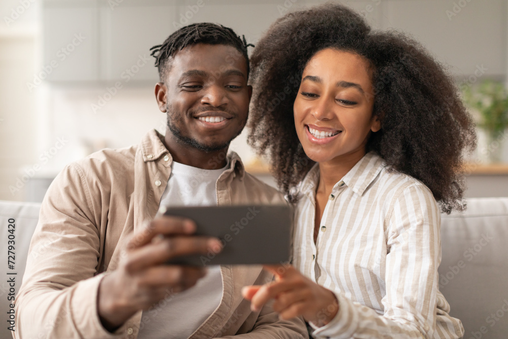 Cheerful Black Millennial Couple Using Smartphone Making Selfie At Home