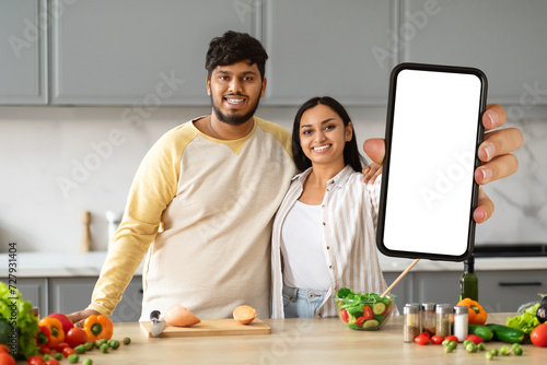 Beautiful loving spouses making food, watching video content on phone