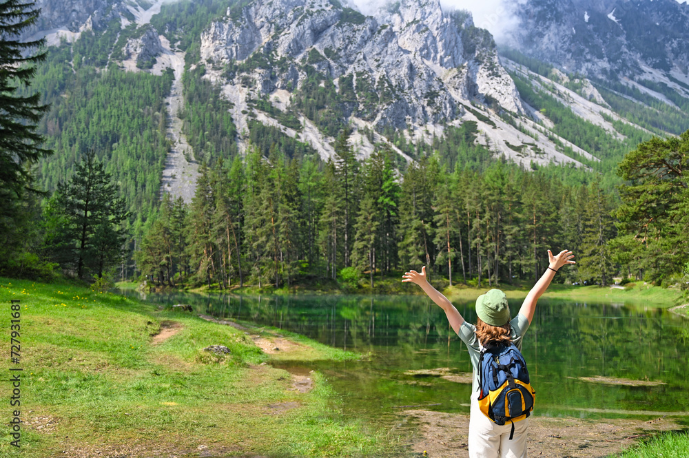 girl with backpack and hands up on Green lake Austria springtime