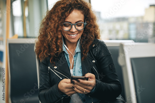 Smiling young woman with glasses listening to music on the metro photo