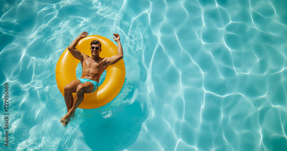A cheerful man waves while sitting on a bright yellow inner tube in the sparkling blue waters of a swimming pool.