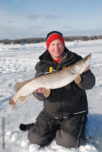 Ice fisherman with a trophy pike caught on a tip-up. 