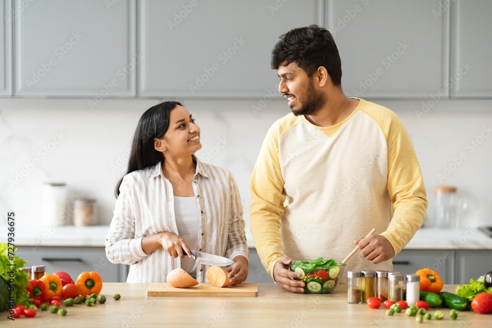 Happy young indian couple preparing healthy vegetarian food at home