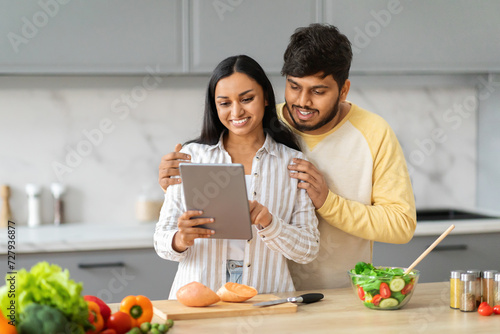 Happy eastern man and woman using tablet white cooking