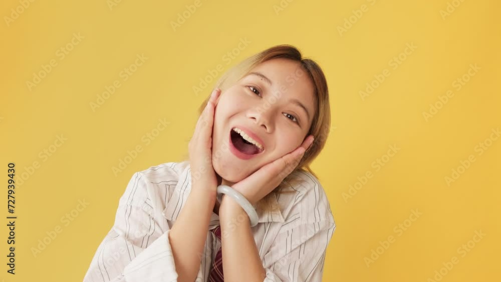 Surprised young woman covering mouth with her hand, clapping her hands isolated on yellow background Surprised young woman covering mouth with her hand, clapping her hands isolated on yellow background