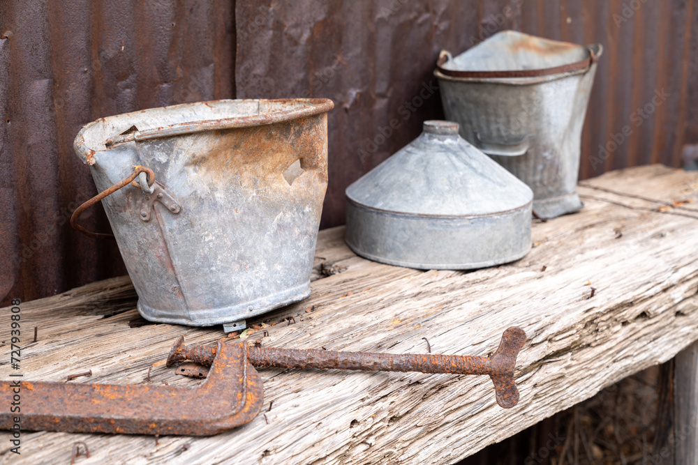 Old rusty dented metal bucket sitting on a wooden table with rusty nails Old rusty dented metal bucket sitting on a wooden table with rusty nails