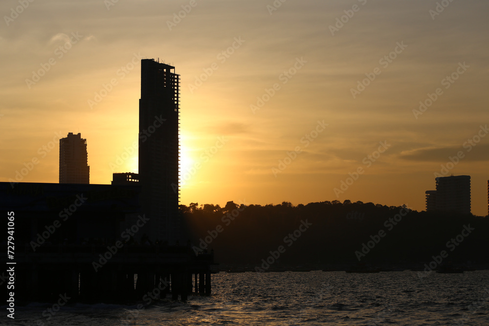 Silhouette picture of Tall buildings and mountains in the evening sun is about to set.