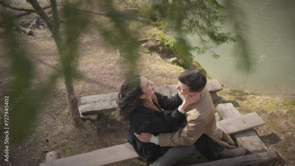 A couple has a date during a spring morning, listening to birds singing and expressing their love, sitting amidst green nature in a park in the forest on a bench. Guy and girl hugging A couple has a date during a spring morning, listening to birds singing and expressing their love, sitting amidst green nature in a park in the forest on a bench. Guy and girl hugging