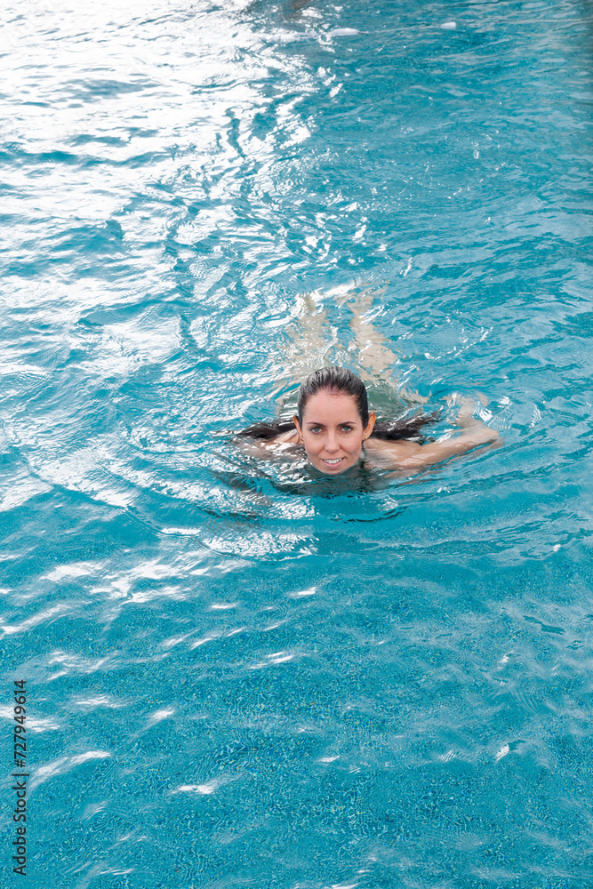 Woman swimming in pool looking at camera