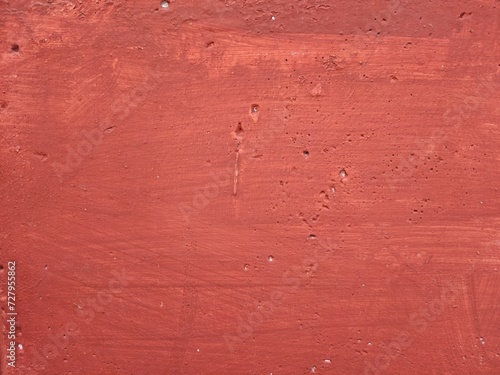 Close-up of the wall painted orange. The textured surface of the wall is red.