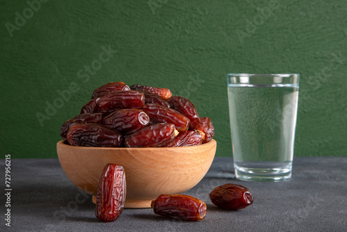 Traditional iftar table with dates and a glass of water, in front of a green background photo