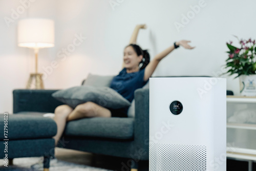 PM2.5 HEPA and virus in home,for fresh air and healthy Wellness life. Woman using air purifier in her house. air purifier while staying and relaxing in the living room. photo