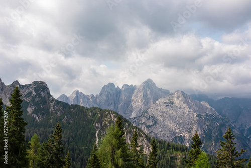 Panoramic view from Monte Lussari in Camporosso, Friuli Venezia Giulia, Italy. Looking at majestic mountain peaks of Julian Alps. Massive rock ridges of Jof Fuart, Cima di Riofreddo covered by clouds © Chris