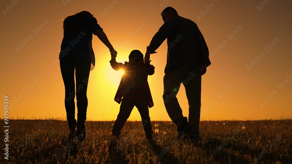 Family walk in spring. Happy family dad mom child go walk in meadow, kid holding parents hands on sunny day. Father mother child play together in nature. Little daughter family play in park. Childhood