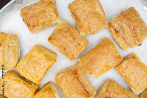 freshly baked puff pastry squares with cheese in tray photo