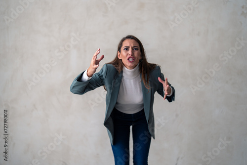 Portrait of an angry business woman yelling against a grey background in a studio. Her temper is rising by the second.
