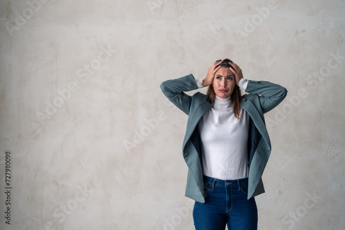 Devastated female professional holding hands on the head feeling overworked, frustration, anxiety, headache, having a problem. Worried business woman standing against background with copy space.