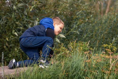 A little boy in blue clothes stumbles in nature during a trip
