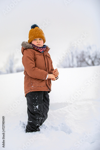Fotografie A disobedient child standing in the snow without gloves, he stubbornly does not