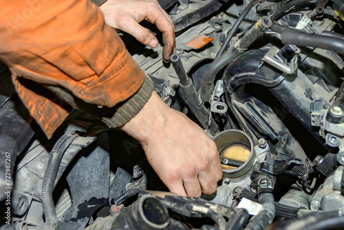 Locksmith-mechanic repairs a car in a car repair shop.