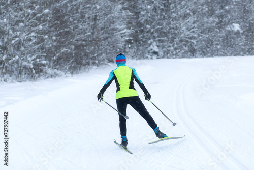 People ski in winter on a ski track through a winter forest.Cross Country skiing.