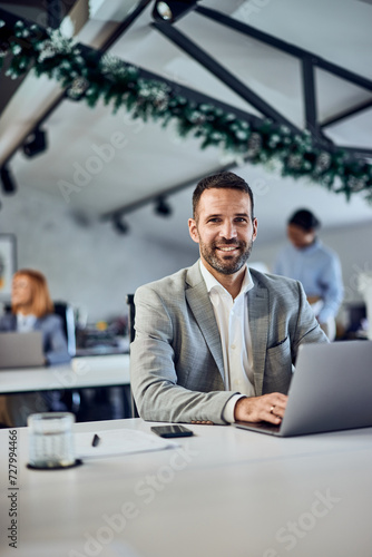 Portrait of an adult smiling businessman looking at the camera, working surrounded his colleagues.