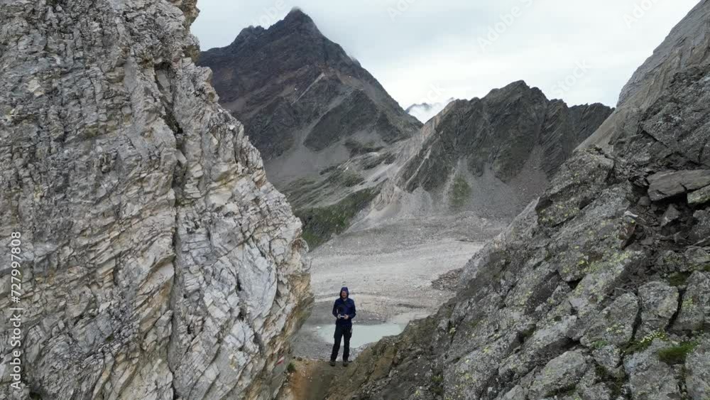 Drone flight through col Johannesscharte (Forcella Giovanni) with male hiker (man) controlling the drone towards mountain panorama in Texel group, South Tyrol, Italy