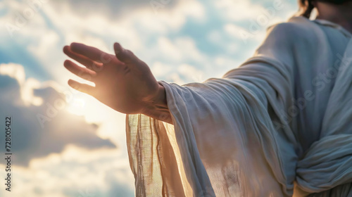 Jesus Christ in white clothes extends his hand to you against the sky as a symbol of Christianity photo