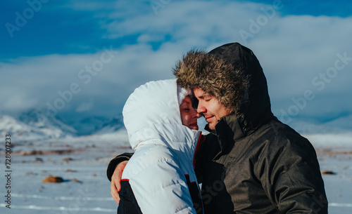 Young romantic couple embracing on mountains background in winter