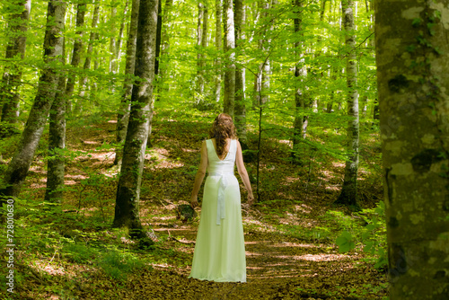 Bride in white dress walking through the spring forest in La Fageda d en Jorda, La Garrotxa, Spain