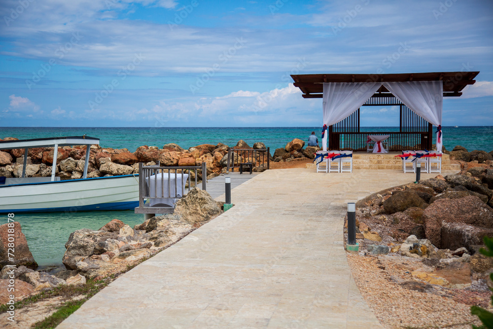 Obraz premium Fishing boat docked by a gazebo along the ocean 