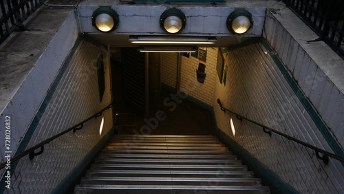 Entrée ou sortie de métro parisien ou de RER, rampe d'escalier avec appuie-main, début de soirée, éclairage de lampadaire, vide, personne, transport urbain, écologique, environnement urbain 