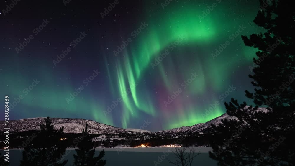 Aurora dancing vividly above a snow covered lake and a mountainous landscape in Bodø. Aurora dancing vividly above a snow covered lake and a mountainous landscape in Bodø.