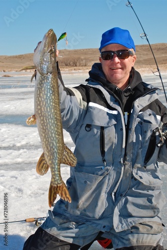 Ice angler landing a winter pike