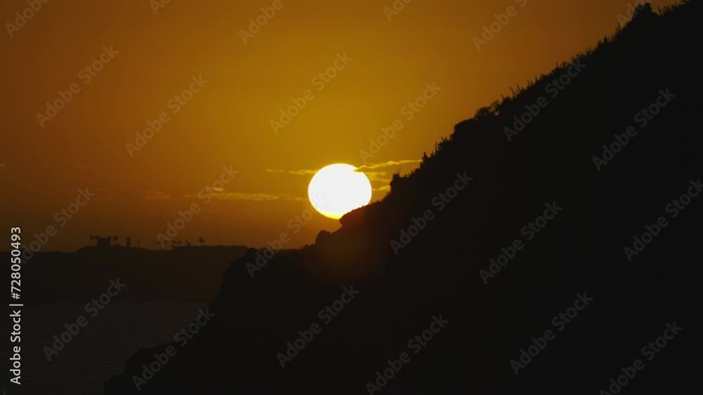 Epic large orange sunset over cliffs and ocean Epic large orange sunset over cliffs and ocean