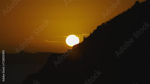 Epic large orange sunset over cliffs and ocean