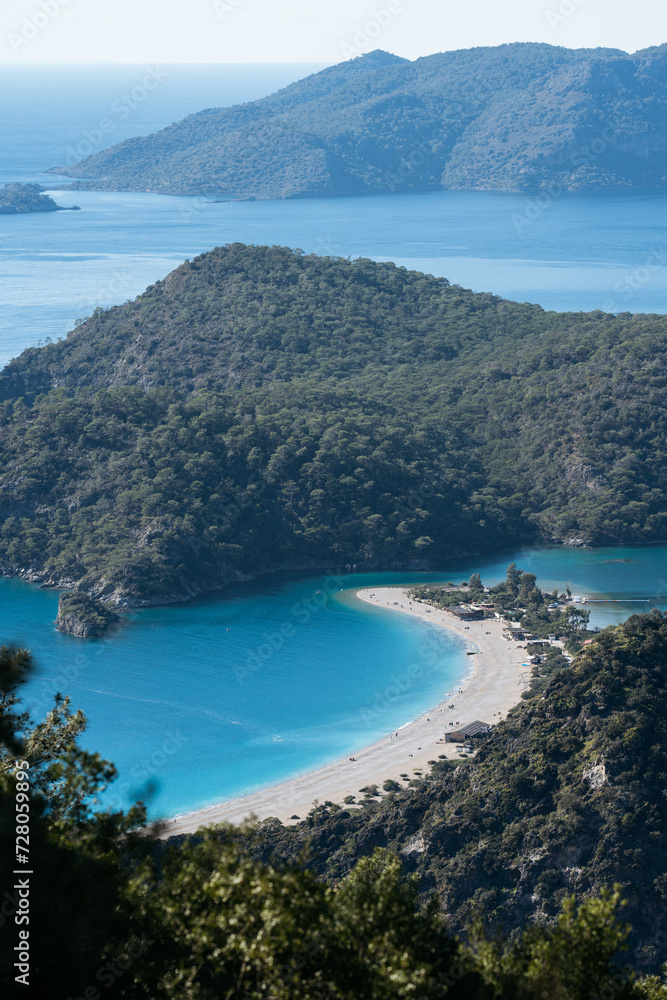 Overhead perspective of Oludeniz Beach, showcasing its distinctive turquoise waters and encircling green hills.