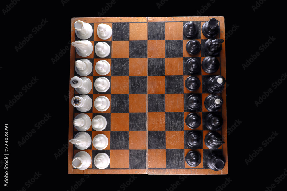 Old chessboard with pieces on an isolated black background. View from above Old chessboard with pieces on an isolated black background. View from above